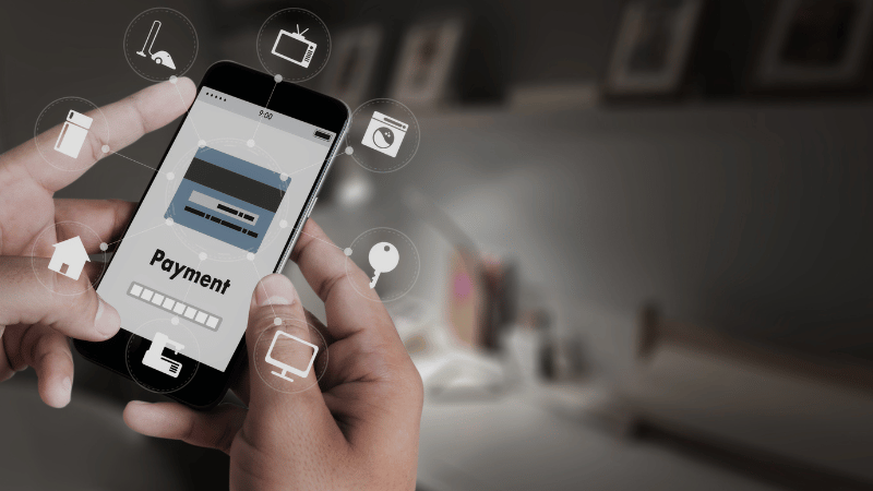 Image representation of payment tokenization: A man holding his smartphone, making payments to various sites